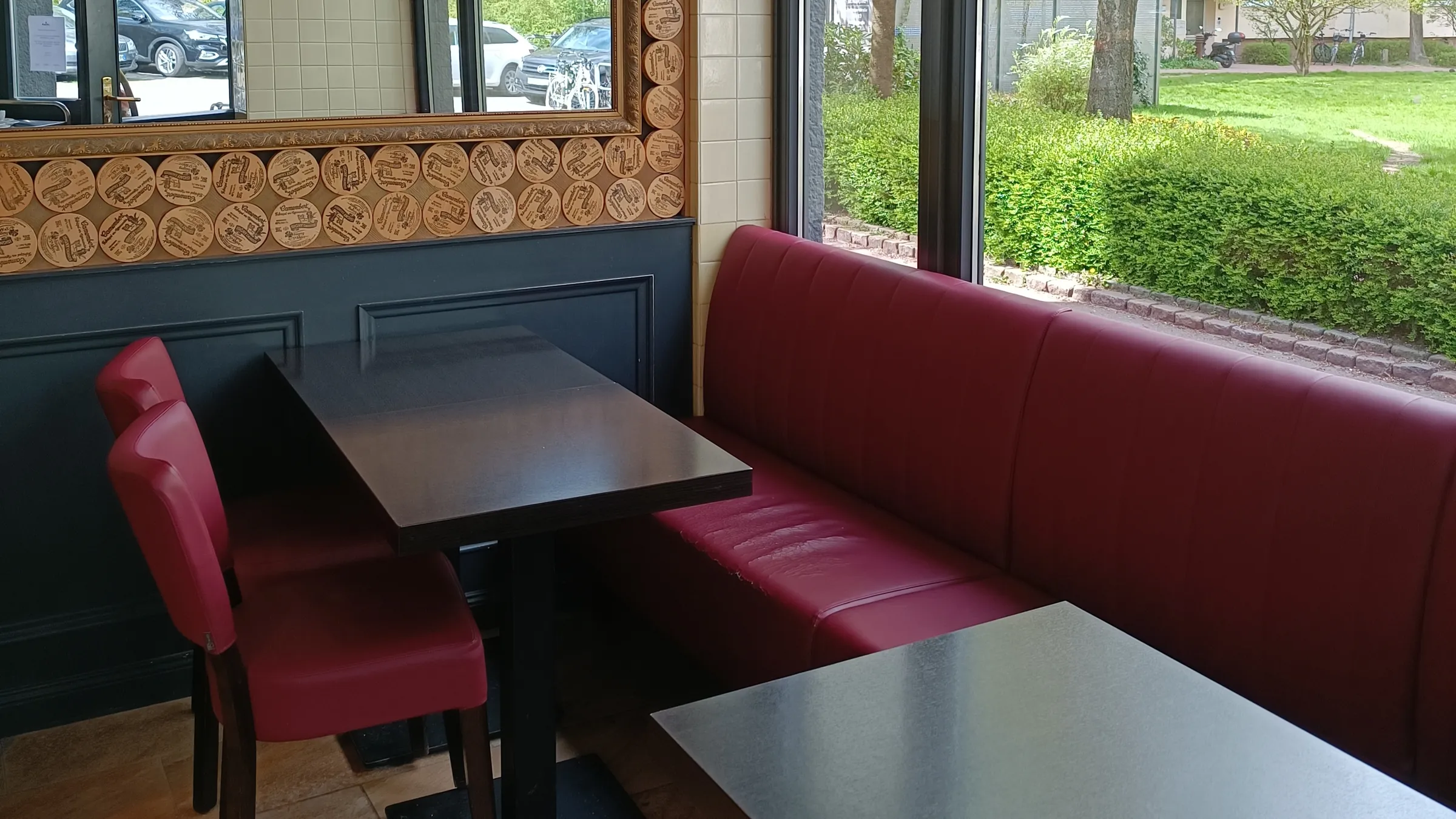 Innenraum des à table mit Sitzbank, roten Stühlen und Fenster zum Grün